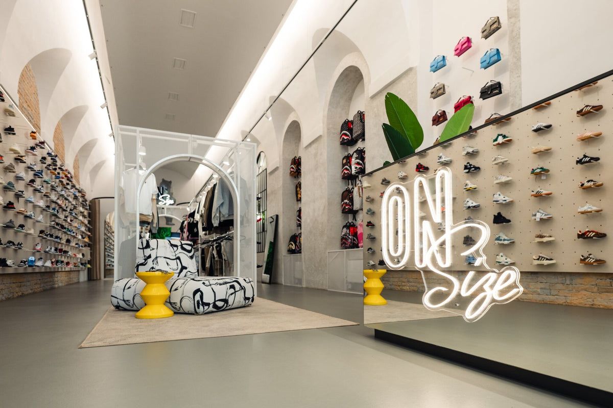 OnSize neonfelirat a tükrös pulton, mögötte táskák és sneakerek