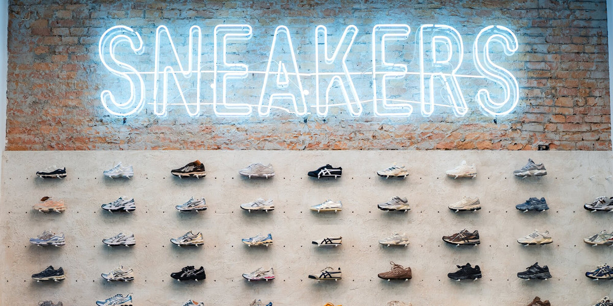 SNEAKERS neonfelirat a téglafalon, alatta sorakozó sneakerek